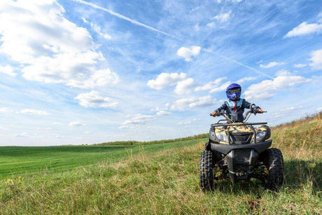 a person riding an atv on a grassy hill